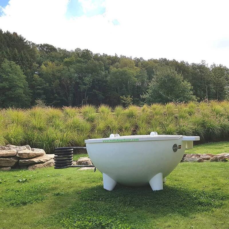 Witte Dutchtub op een grasveld voor een bosrand