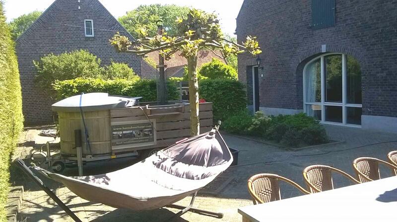 Vaste hottub op een zonnig terras met hangmat en tuinstoelen